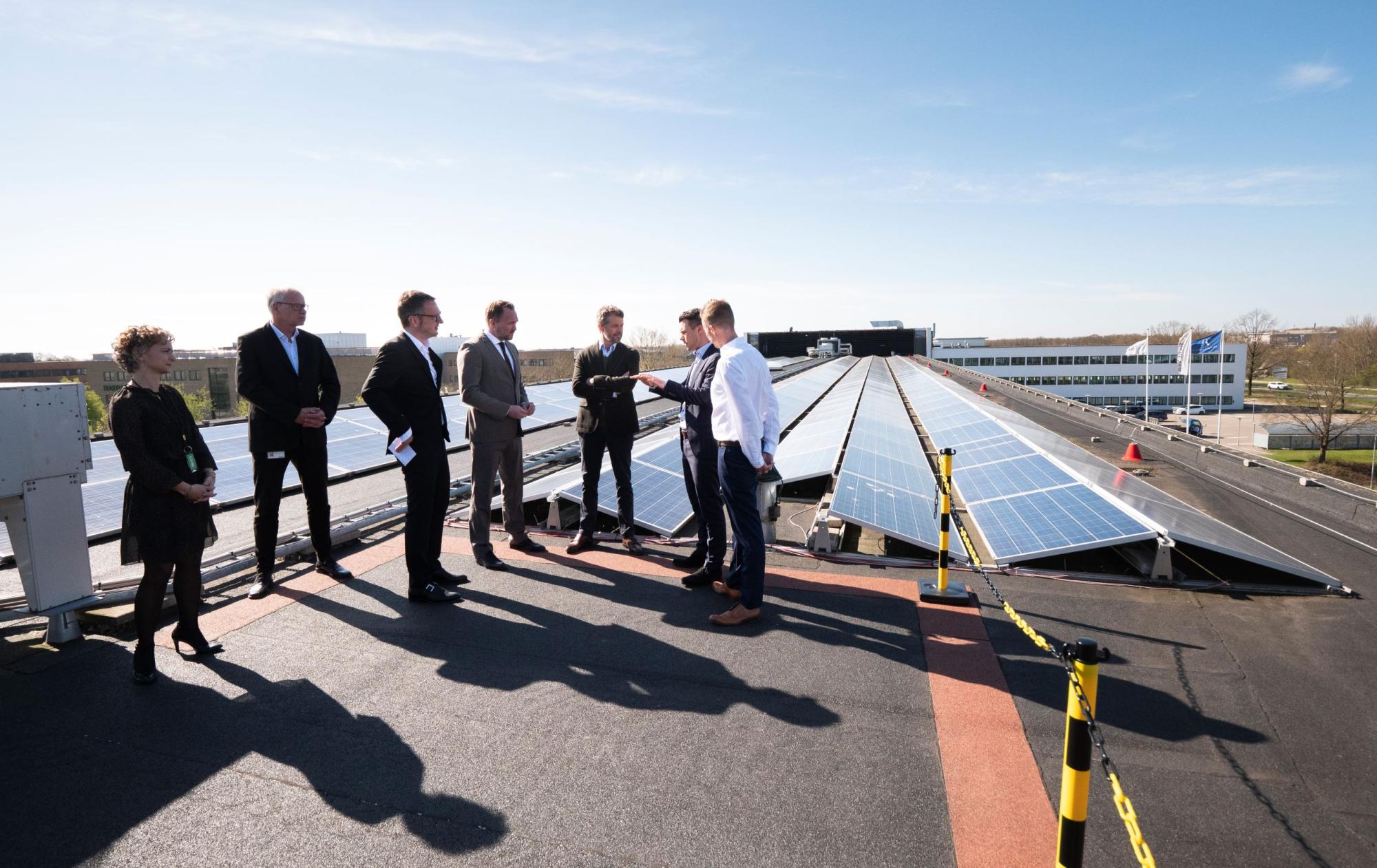 En masse mennesker på et tag foran solceller