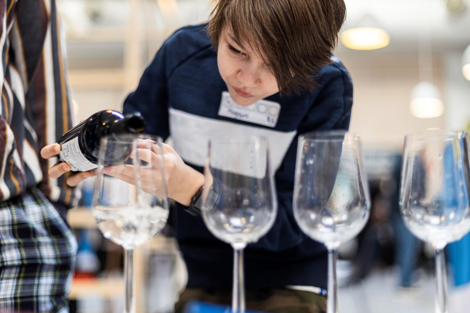 En dreng hælder vin i et vinglas