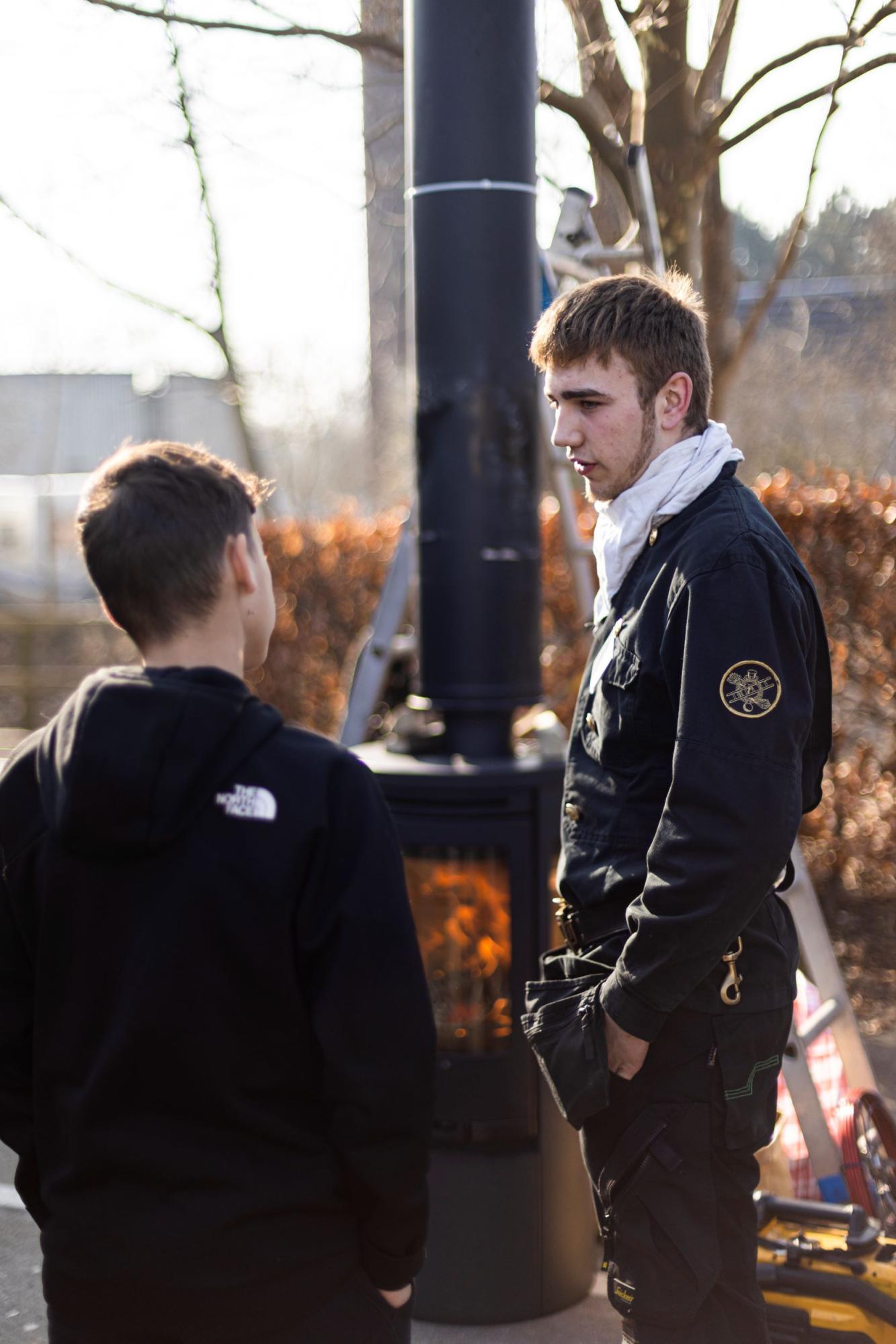 To mænd snakker foran en skorsten