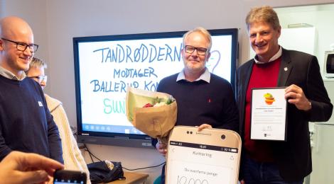 To mennesker holder en check. Tandrødderne vandt Sundhedsprisen 2021.
