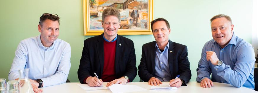 Fire mænd sidder ved et skriveborg