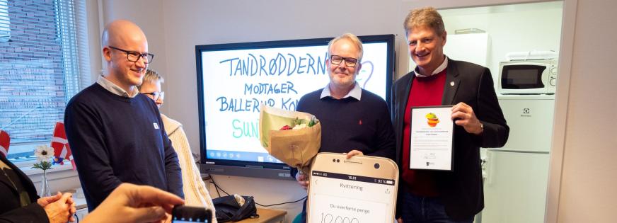 To mennesker holder en check. Tandrødderne vandt Sundhedsprisen 2021.